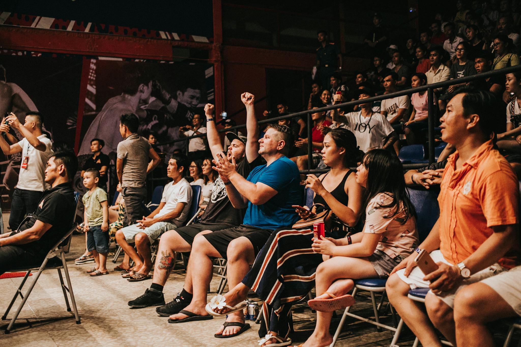 Excited crowd cheering and clapping at an indoor sports event, capturing the energy and enthusiasm.